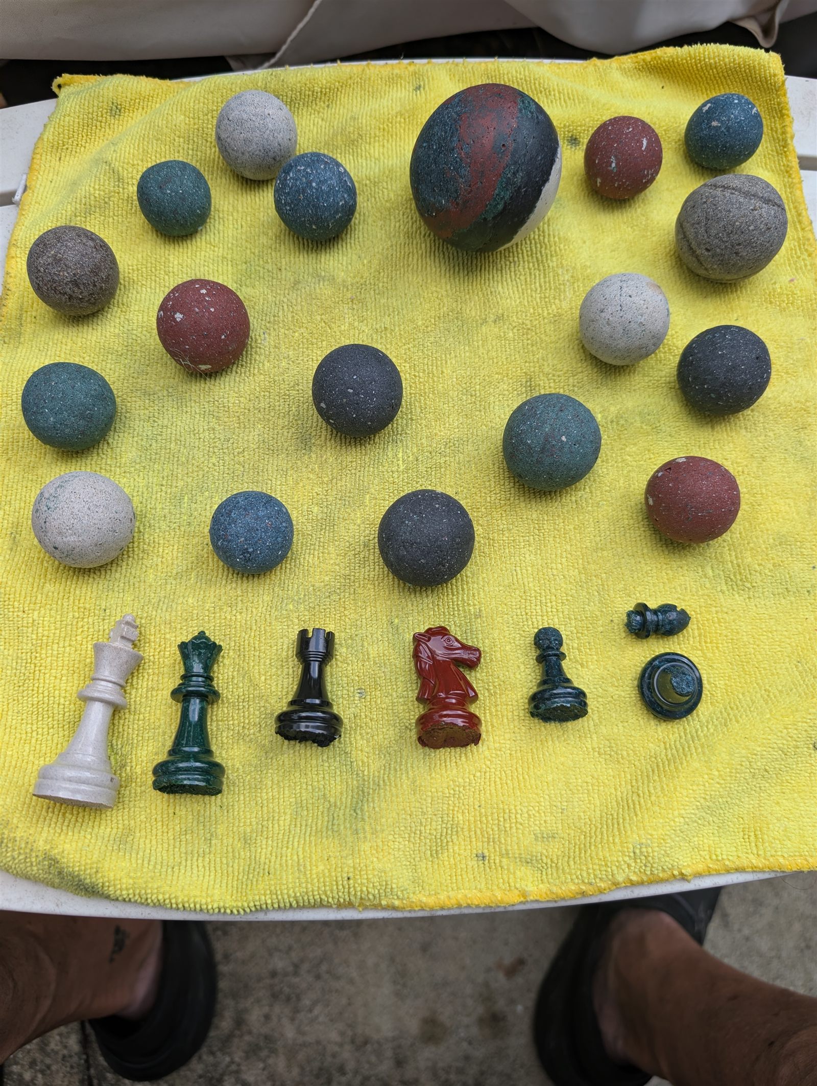Two dozen hand-rolled memorial pearls in slate blue, terracotta, sage, bone and charcoal, beside hand-cast chess pieces.